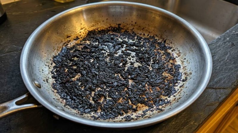 Step-by-step process of cleaning a burnt stainless steel pan with baking soda and vinegar on a kitchen counter