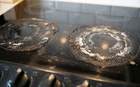 Person cleaning an electric stove top with microfiber cloth