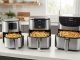 Three air fryers of different sizes open on a bright kitchen counter.