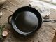 A glossy black cast iron skillet with a non-stick seasoned coating on a wooden counter.