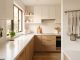 A modern small kitchen featuring clear countertops, wall knife strip, and hanging utensils.